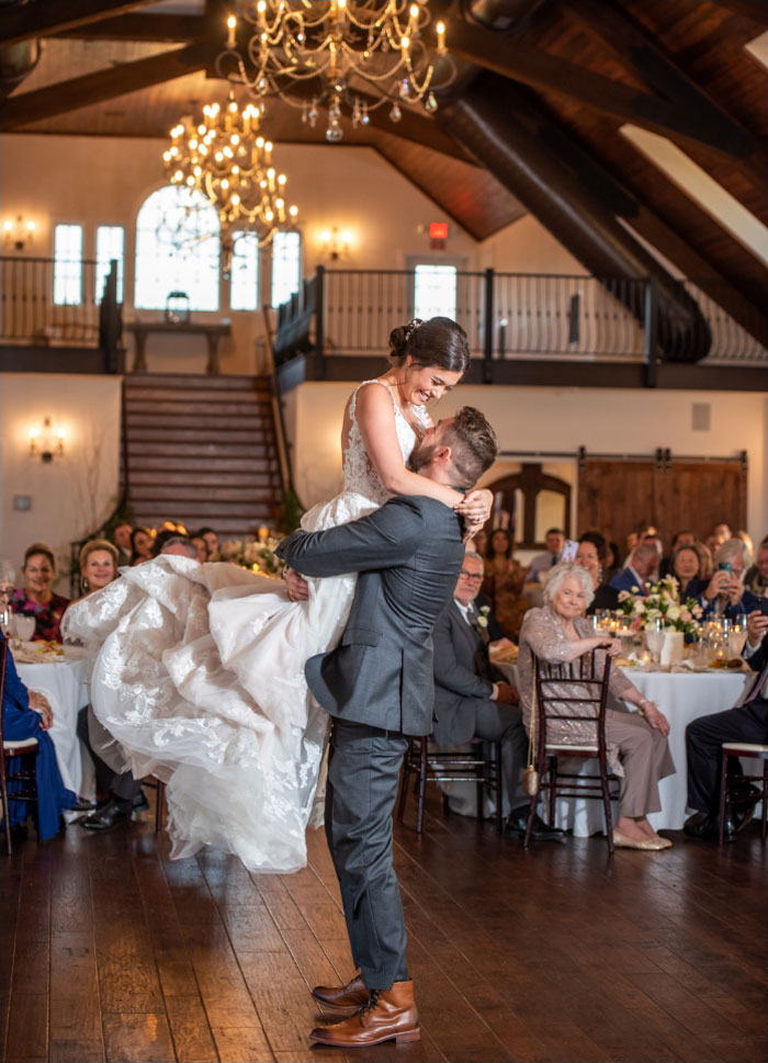 Groom raising bride in the air at reception