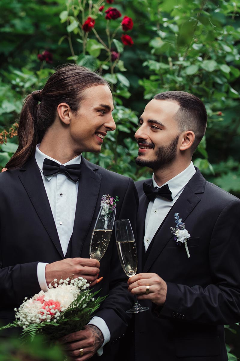 happy gay couple in suits holding glasses of champagne